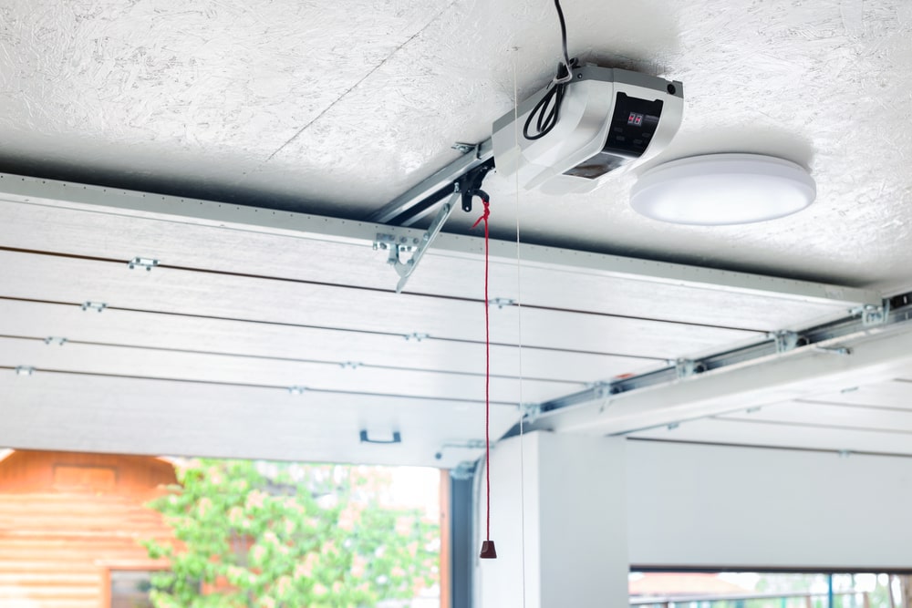 Automatic garage door and ceiling-mounted electric motor with emergency cord on a sloped entrance door