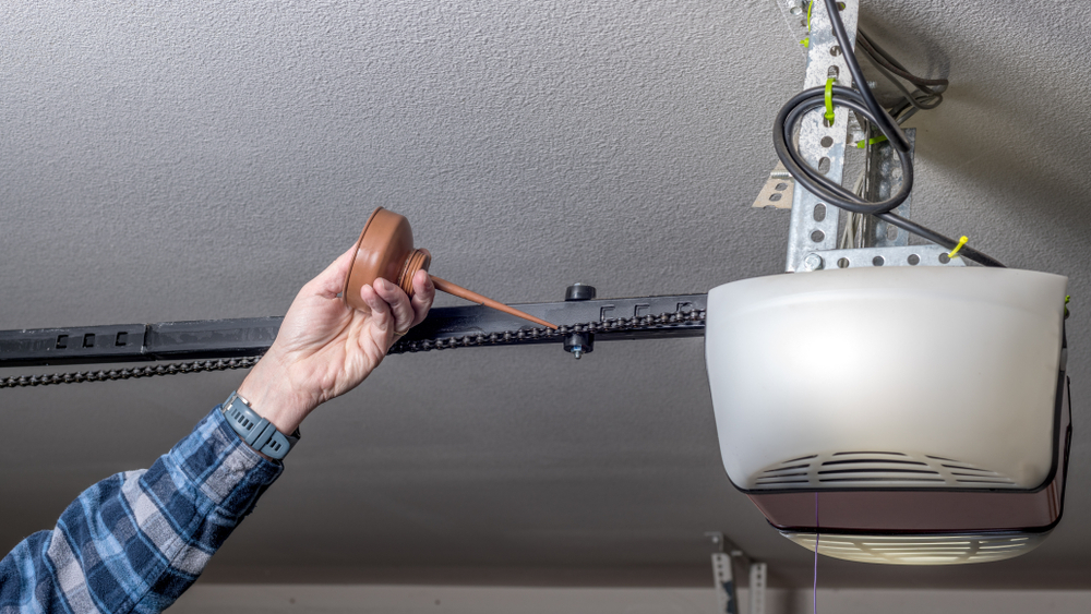 Performing Maintenance on a Garage Door Opener Chain by Applying Lubricant for Smooth Operation in New Orleans.