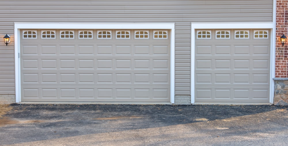 Charcoal gray insulated steel raised panel garage doors with white trim and transom light windows, enhancing a modern American home.