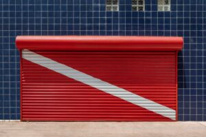 Closed store shutter painted to red - solid garage door - hurricane garage door