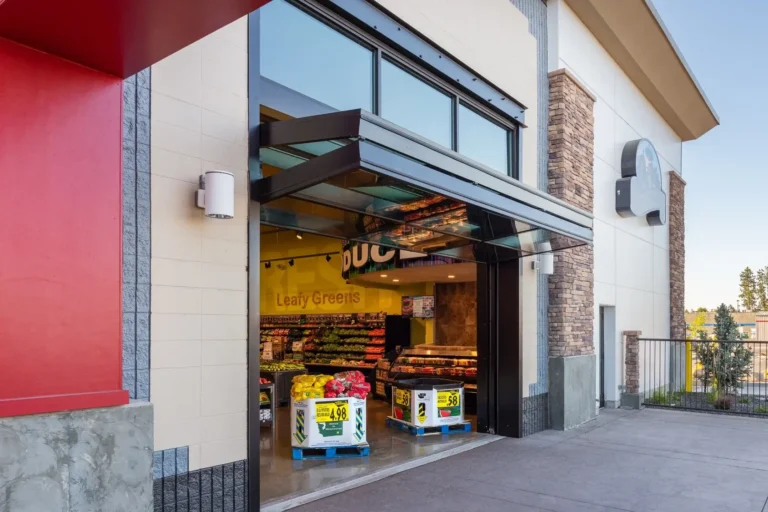 Commercial glass folding garage door installation at a grocery store entrance - ace garage door